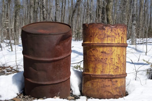 Two rusty iron barrels left in the forest.