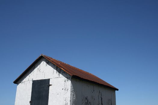 White rural hut and spacious blue sky (barn on the farm).