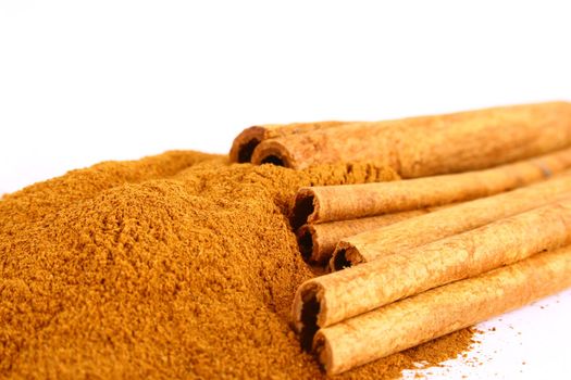 Sticks and powder of cinnamon reflected on the white background