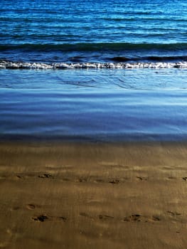 Water waves washing up onto the sandy beach.