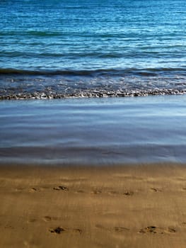 Water waves washing up onto the sandy beach.