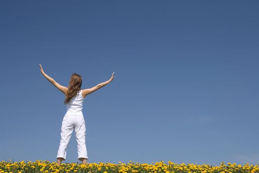 Young woman exercising outdoors, in a flowering spring field.