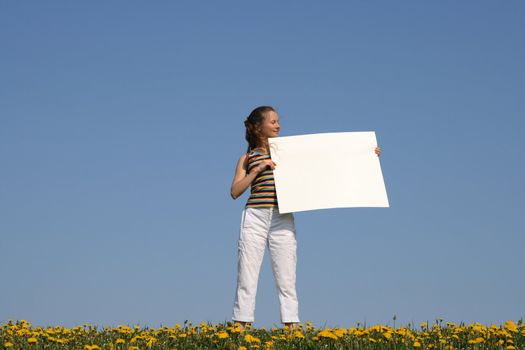 Pretty girl in dandelion field holding blank banner with copy space.