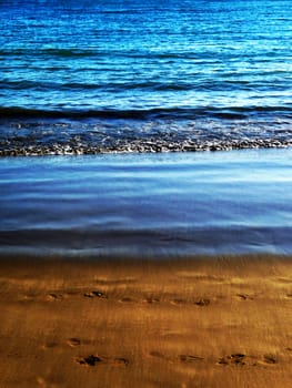 Water waves washing up onto the sandy beach.