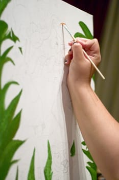 A closeup of a young woman painting on a canvas.