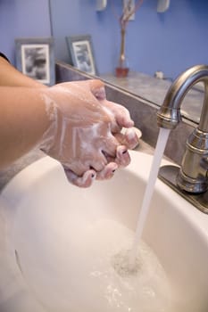 A person washing their hands in the bathroom.