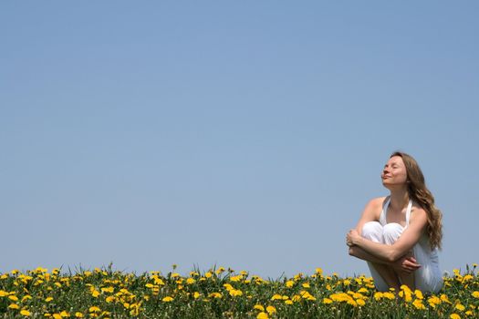 Young woman enjoying sunshine in a flowering spring field.