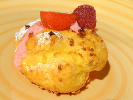 Puff dough filled with berries cream , decorated with strawberry, raspberry and icing sugar