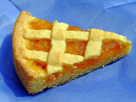Slice of apricot marmalade tart on a blue paper napkin
