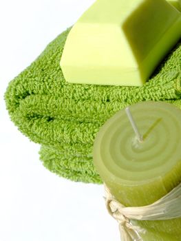 Two green towels a piece of green soap and a green candle on white background
