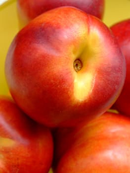 Close-up of ripe peaches in a yellow plastic basket