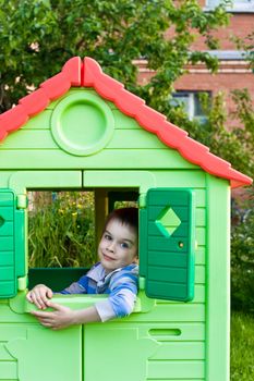 Young boy smiling in plastic house window at playground