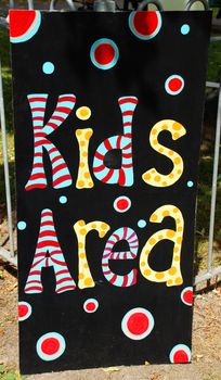 A photograph of a sign for a 'kids' area', situated outdoors in front of the fence around a play park