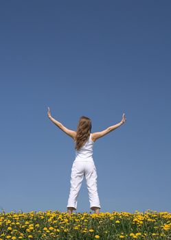 Young woman exercising outdoors in flowering dandelion field.