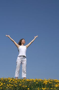 Young woman in flowering spring field greeting the sun.