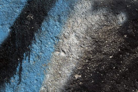 Black and blue graffiti on a grainy concrete wall. Abstract background.