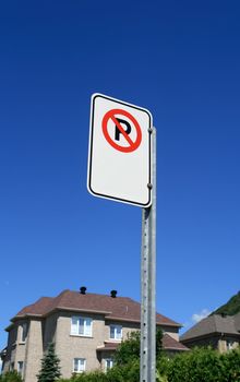 No parking sign in front of a new expensive house in a suburban neighborhood.