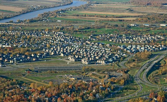 Aerial view of a suburban neighborhood and highway in bright colors of autumn.