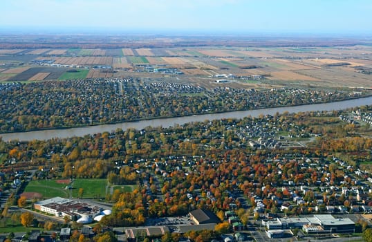 Aerial view of a town near river in bright colors of autumn.
