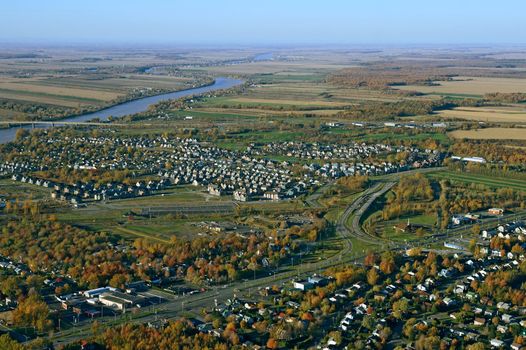 Aerial view of suburban neighborhood near highway in autumn.