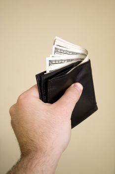 A hand holding a wallet full of cash isolated over a bold background