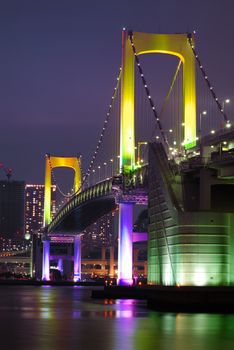 one of famous Tokyo landmarks, Tokyo Rainbow suspension bridge supports over night waters with scenic colorful illumination