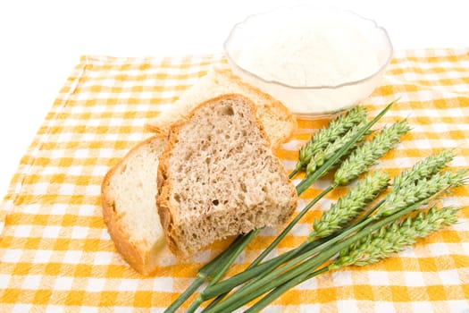 Bread, flour and green wheat on table cover.