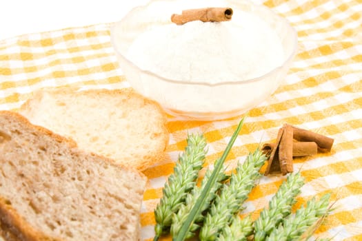 Bread, flour and green wheat on table cover.