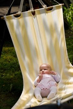 Baby swinging in striped hammock on a summer day