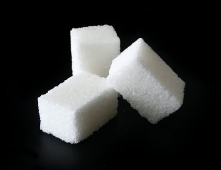 Three pieces of sugar on a black background.