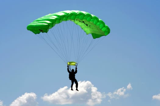 Parachuter  with green parachute on sky background 