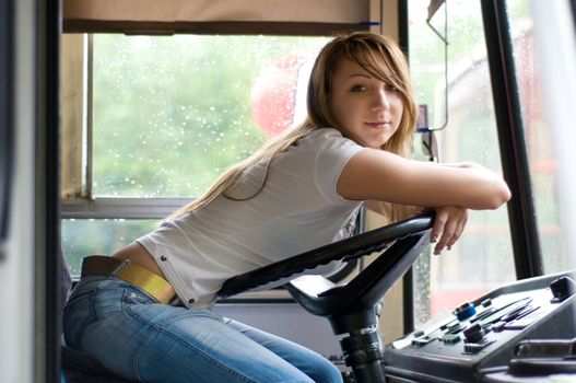 cute young girl sitting at trolleybus cabin and holding the steering wheel