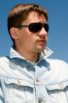 young man in sunglasses against the sky