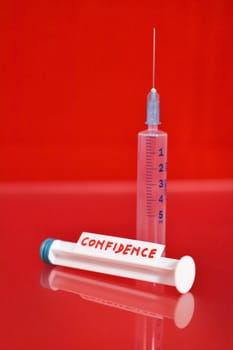 Syringe and word confidence against red background