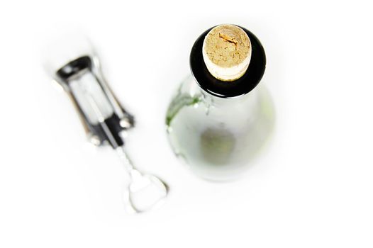 Corkscrew and white wine bottle on white, shallow DOF