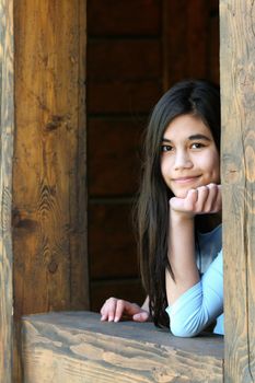 Beautiful young teen girl relaxing on porch, part asian, scandinavian background