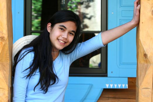 Beautiful young teen girl relaxing on porch, part asian, scandinavian background