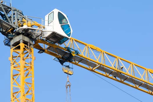 high yellow construction crane against the clear blue sky