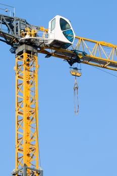 high yellow construction crane against the clear blue sky, lot of copyspace