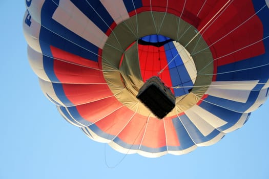 hot-air balloon with basket rises in the sky 