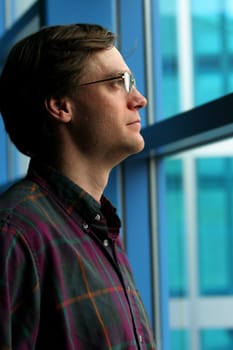 Businessman looking out blue glass window