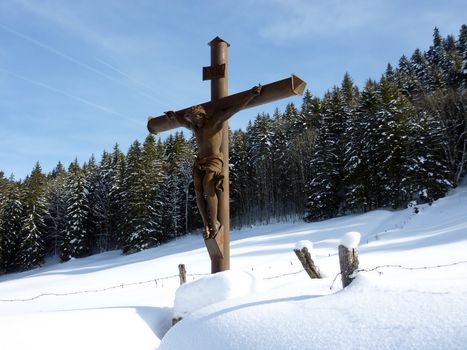 Jesus cross surrounded by snow and fir trees by winter