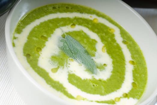 fresh spinach soup on a white bowl with sage and cream on top