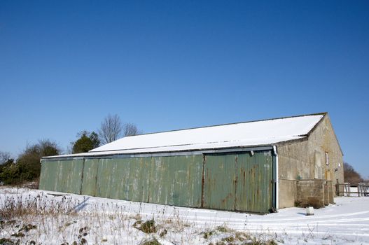 A barn covered in snow with a clear blue sky