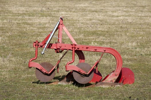 An old plough in a field of grass