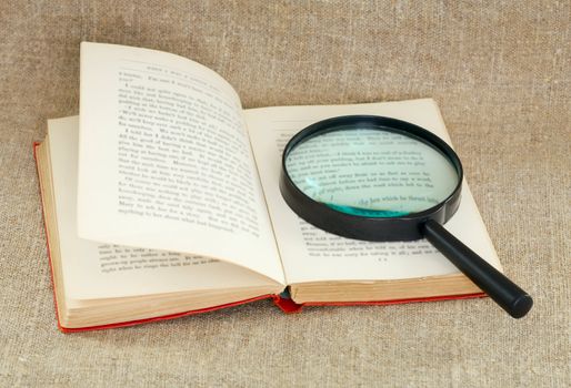 Still life of a magnifying glass and an old book on canvas