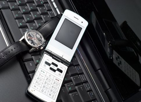 Cellular phone and watch on a laptop