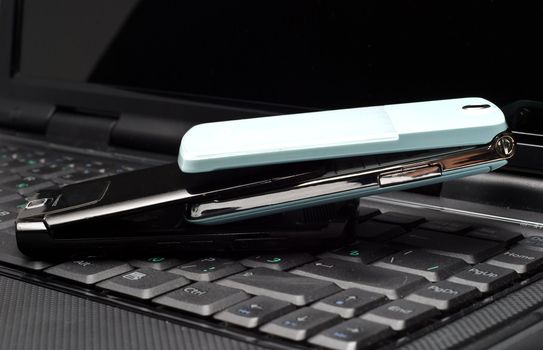 Two Cellular phones on a laptop