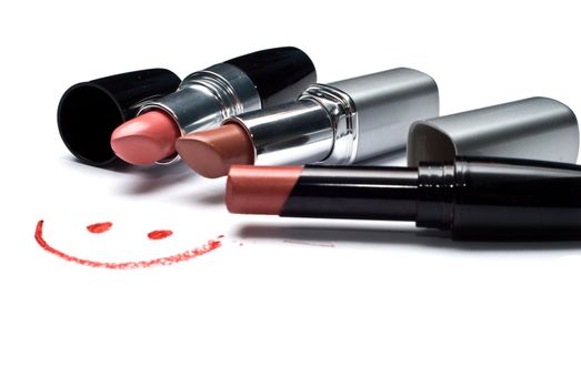 three lipsticks and smile on a white background