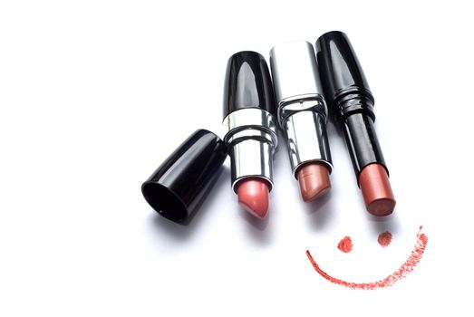 three lipsticks and smile on a white background